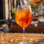 Aperol Spritz i ballongglas på uteservering med apelsinskiva och is